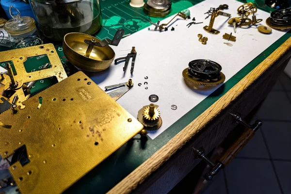 Naprawa zegara – rozebrany mechanizm zegarowy na warsztacie zegarmistrza