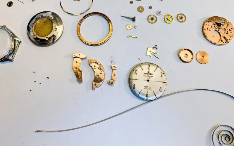 Rozłożony mechanizm zegarka Atlantic z częściami – profesjonalny serwis i naprawa zegarków